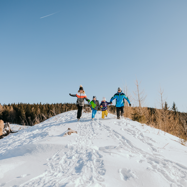 Familie läuft durch die verschneite Winterlandschaft