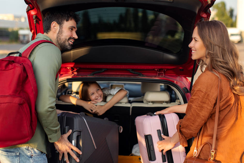 Parents packing luggage in trunk of car with kid girl sitting on backseat and looking at mother and father, family going on vacation | © TV Suedsteiermark | (c) TV Südsteiermark - AdobeStock_359694212
