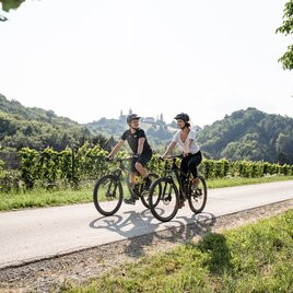 Ein Pärchen mit dem Rad auf der Sausaler Tour von Weinbergen umgeben