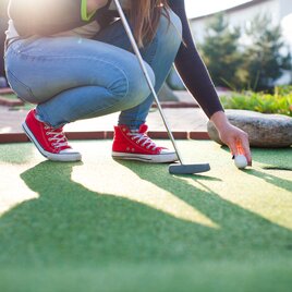 Dame mit roten Converse Chucks spielt Minigolf