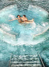 Ein Paar entspannt sich in einem Sprudelwasserbecken im Asia Spa, Er hält sie im Wasser in den Armen