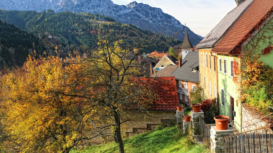 Herbstliche Aufnahme der Kirchenstiege zur Wehrkirche St. Oswald in Eisenerz umgeben von Häusern und Bergen