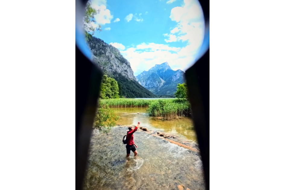 Ein Mann, der in einem See steht und mit Wasser spritzt vor einem schroffen Berggipfel, eingerahmt von einem schwarzen Schloss. | © Manuel Bechter | Manuel Bechter