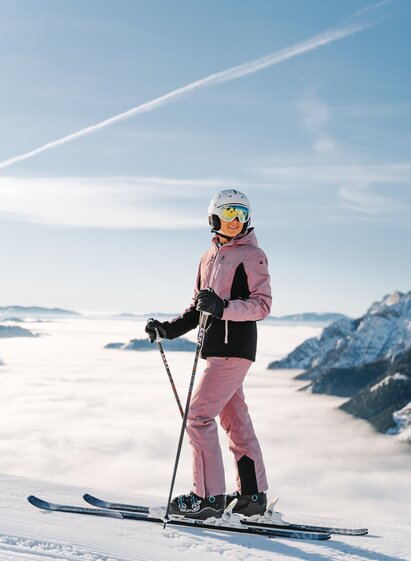Eine Skifahrerin am Start einer Piste über einem nebelverhangenem Tal.