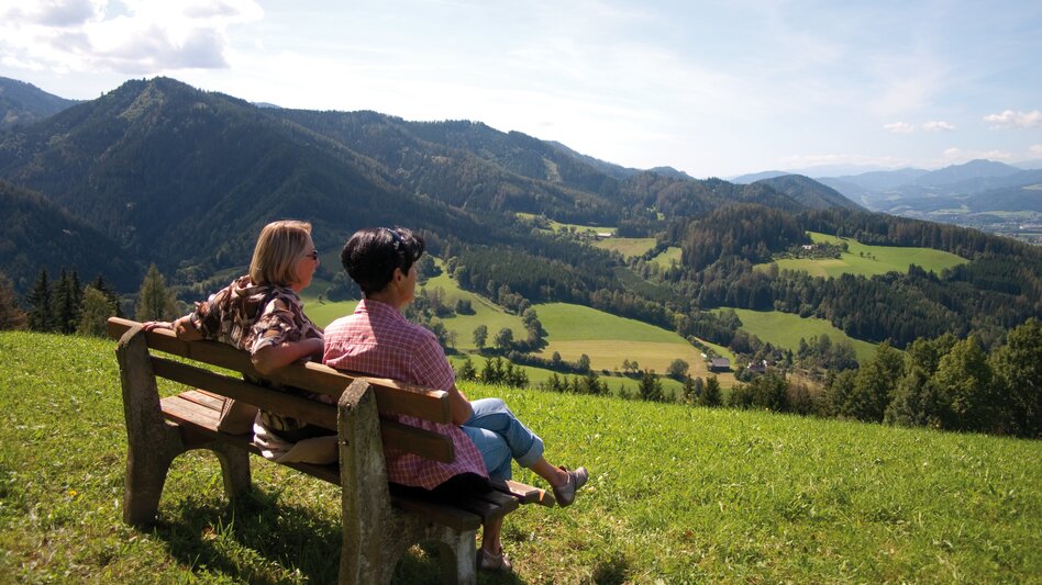 Ein Mann und eine Frau sitzen auf einer Bank und schauen in die Ferne