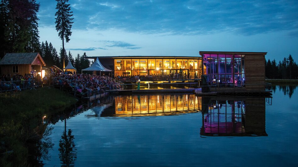 Ansicht der Seebühne auf der Mariazeller Bürgeralpe bei einem Konzert am Abend, im Hintergrund die Arche des Waldes und Zuschauertribünen