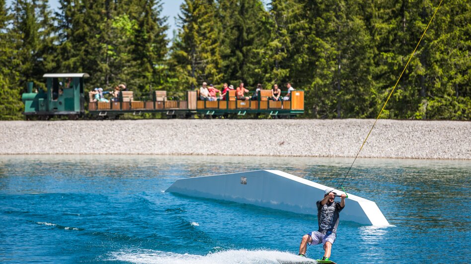 Ansicht eines Wakeboarders auf der Mariazeller Bürgeralpe am Kristallsee, im Hintergrund die Waldeisenbahn