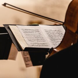 music stand with sheet music, a cello slightly blurred in the foreground