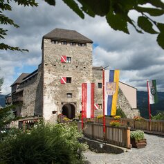 Eine Frau genießt mit ihrem Hund die Aussicht am Gipfelkreuz
