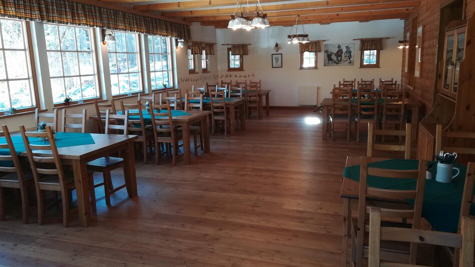 Ein Saal mit mehreren Tischen und schöner Aussicht ins Grüne.