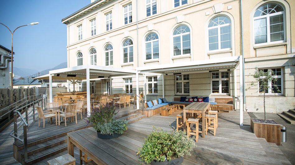 Die Sommerterrasse vom Hotel Böhlerstern in Kapfenberg mit einige Tischen und Stühlen, teilweise überdacht