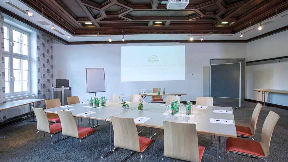 Das Musikzimmer im Hotel Böhlerstern mit Teppichboden und Holzdecke, Leinwand, Beamer, Pinnwand, Flipchart und Tischen mit Stühlen