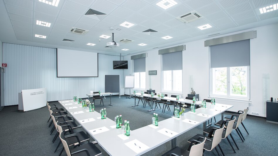 Der Raum "Steel Academy" im Hotel Böhlerstern ganz in silber/grau gehalten mit Teppichboden, Tischen in U-Form mit Sesseln, 3 Fenstern, Beamer, Leinwand, Flipchart und Pinnwand
