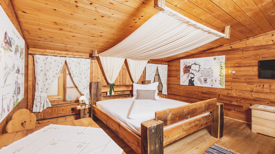 Ansicht eines Doppelzimmers mit großem Himmelbett und Holz-Einrichtung