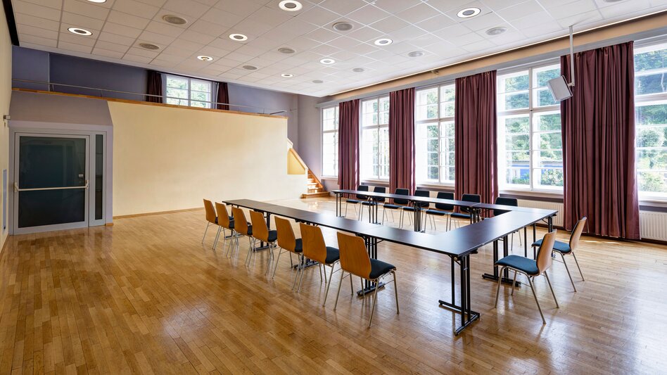 Ansicht des Schlossbergsaales in Bruck an der Mur mit mehreren Fenstern und Tisch mit Sesseln in U-Form