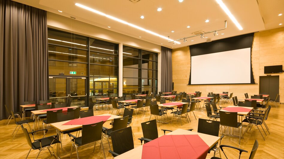 Der Kleine Saal im Veranstaltungszentrum Krieglach mit Blick zur Leinwand und Fensterelementen von der Decke bis zum Boden
