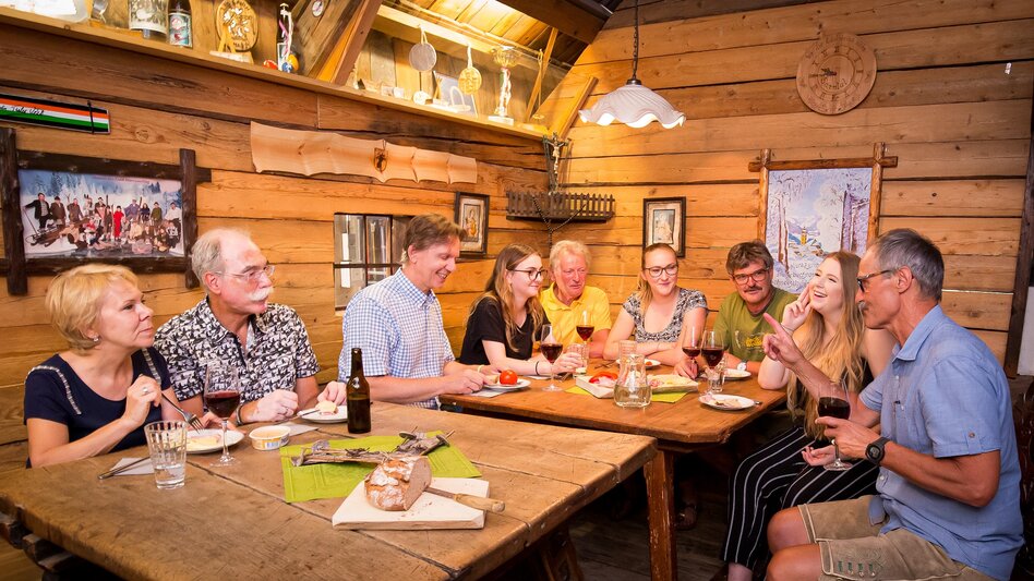 Ansicht der Skihütte im WinterSportMuseum mit 2 Tischen und mehreren Personen beim Jausnen