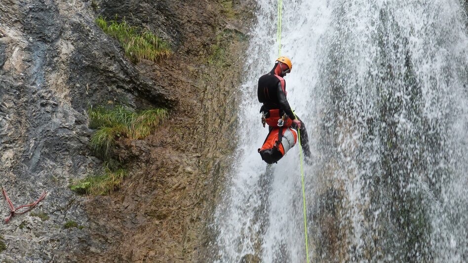 Person beim Abseilen im Wasserfall
