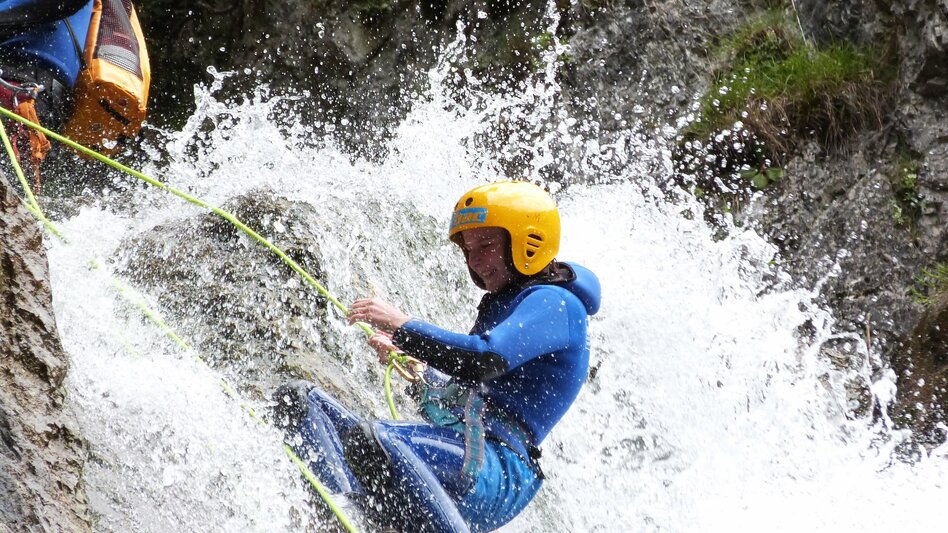 Junge Dame beim Abseilen im Wasserfall