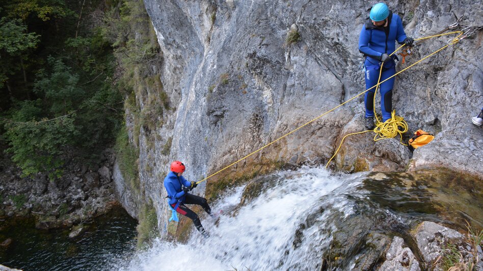Zwei Personen beim Abseilen am Wasserfall