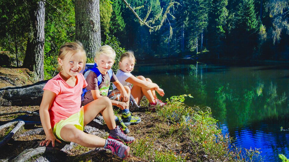 Drei lächelnde Kinder am Teichufer