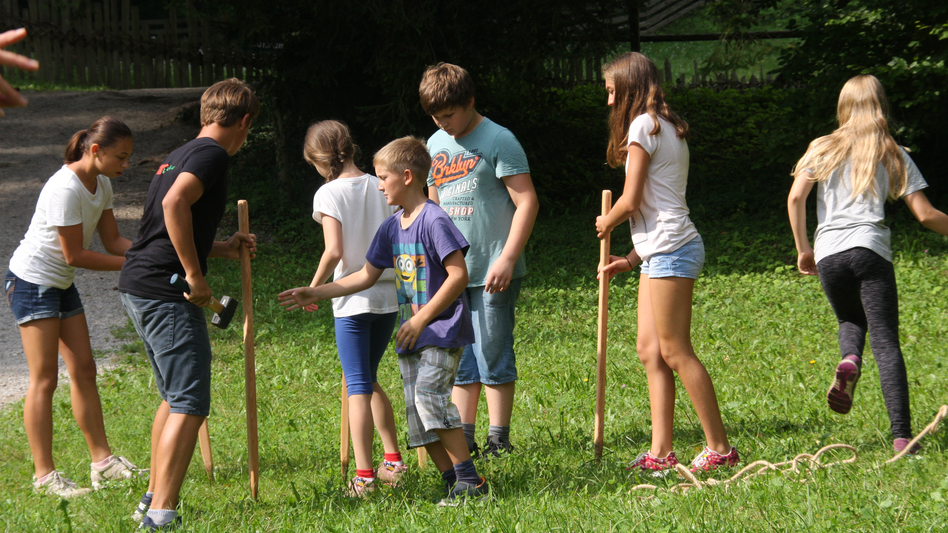 Kinder spielen ein Spiel mit Stöcken auf einer Wiese