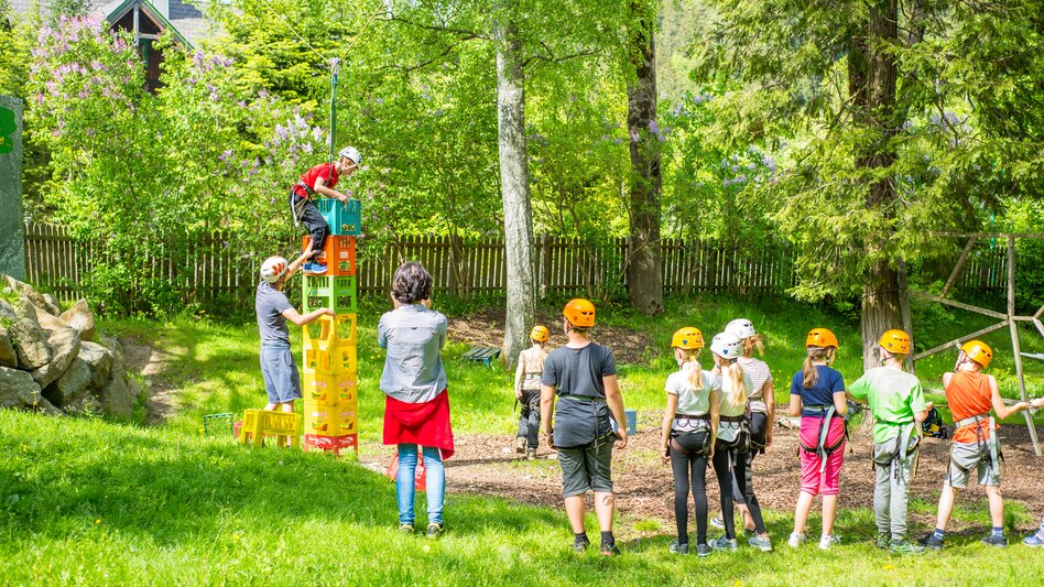 Beim Geschicklichkeitsspiel müssen die Kinder einzeln Kisten übereinanderstapeln und nach oben klettern. Wer schafft am meisten Kisten ohne zu fallen? Die Kinder sind mit Helm und Klettergurt gesichert.