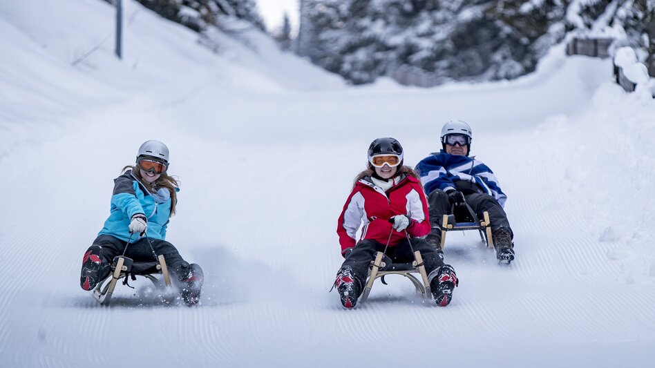 Drei Personen beim Rodeln auf einer Schneepiste | © Salzstiegl Tourismus GmbH