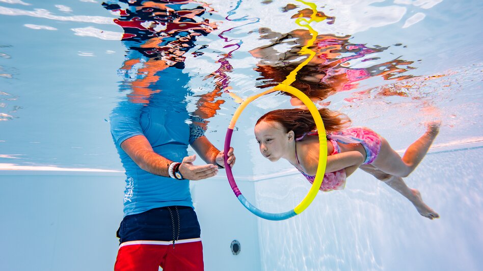 Ein Mädchen taucht durch einen Ring in der H2O Therme
