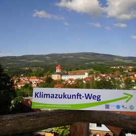 Klimazukunft-Weg: Wegweiser im Hintergrund Schloss und Pfarrkirche Pöllau | © Oststeiermark Tourismus