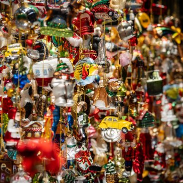 Zahlreiche bunte und glänzende Weihnachtsanhänger hängen dicht an dicht als festliche Dekoration