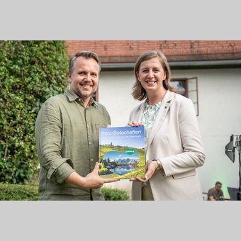LR Barbara Eibinger-Miedl und STG-GF Michael Feiertag mit dem druckfrischen Buch „Herz-Botschaften – Liebeserklärungen an die Steiermark“.  | © STG | Jesse Streibl