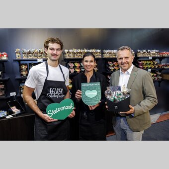 Johannes und Julia Felber gemeinsam mit STG-GF Michael Feiertag im neuen Felber-Shop mit Schokolade-Auswahl. | © STG | Erwin Scheriau