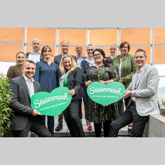 Tourismusbeirat anbei: Die GFs der Erlebnisregionen werden flankiert von STG-GF Michael Feiertag (mit Herz li) und Ingo List, Leiter des Referats Tourismus im Land Steiermark (mit Herz re). Dahinter die GFs Pamela Binder (Ausseerland), Stefan Schindler (Oststeiermark), Jaqueline Egger (Gesäuse), Mathias Schattleitner (Schladming-Dachstein), Claudia Flatscher (Erzberg Leoben), Christian Contola (Thermen- & Vulkanland), Stephanie Zündel (Hochsteiermark), Melanie Koch (Südsteiermark), Peter Mayer (Murau), Manuela Machner (Murtal). | © STG | Jesse Streibl