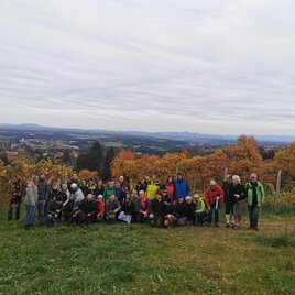 A large group of people stands in a vineyard with autumn colors. In the background, a picturesque landscape stretches out. | © CDM Incoming