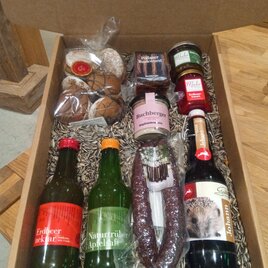 Eine Geschenkbox mit verschiedenen regionalen Lebensmitteln. Sie enthält Getränke, Wurst, Marmelade und Gebäck. | © Familie Muhr
