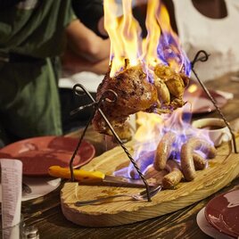 A roasted dish that is prepared over an open fire. Flames surround the meat and the atmosphere is sociable. | © Schlosswirt Kornberg/Skalnik
