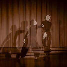 Eine tänzerische Darbietung mit einer Person auf der Bühne. Die Schatten der Bewegung erzeugen einen dynamischen Effekt vor einem roten Vorhang. | © Gudrun Bartoska