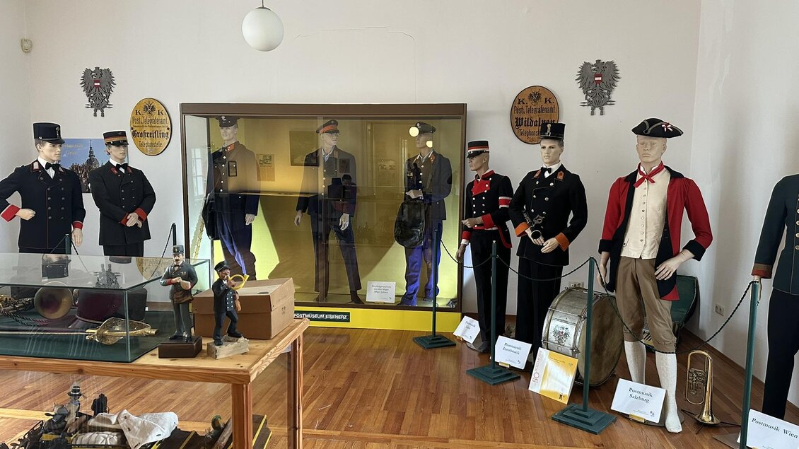 Ein Museum mit historischen Uniformen aus verschiedenen Epochen ist zu sehen. Im Vordergrund stehen Vitrinen mit Ausstellungsstücken und Instrumenten. | © Mandl