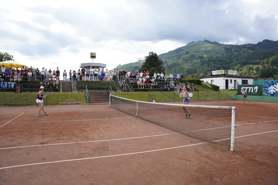 Zwei Spielerinnen spielen Tennis auf einem Sandplatz. Eine Gruppe von Zuschauern verfolgt das Spiel im Hintergrund. | © Stadt Bruck