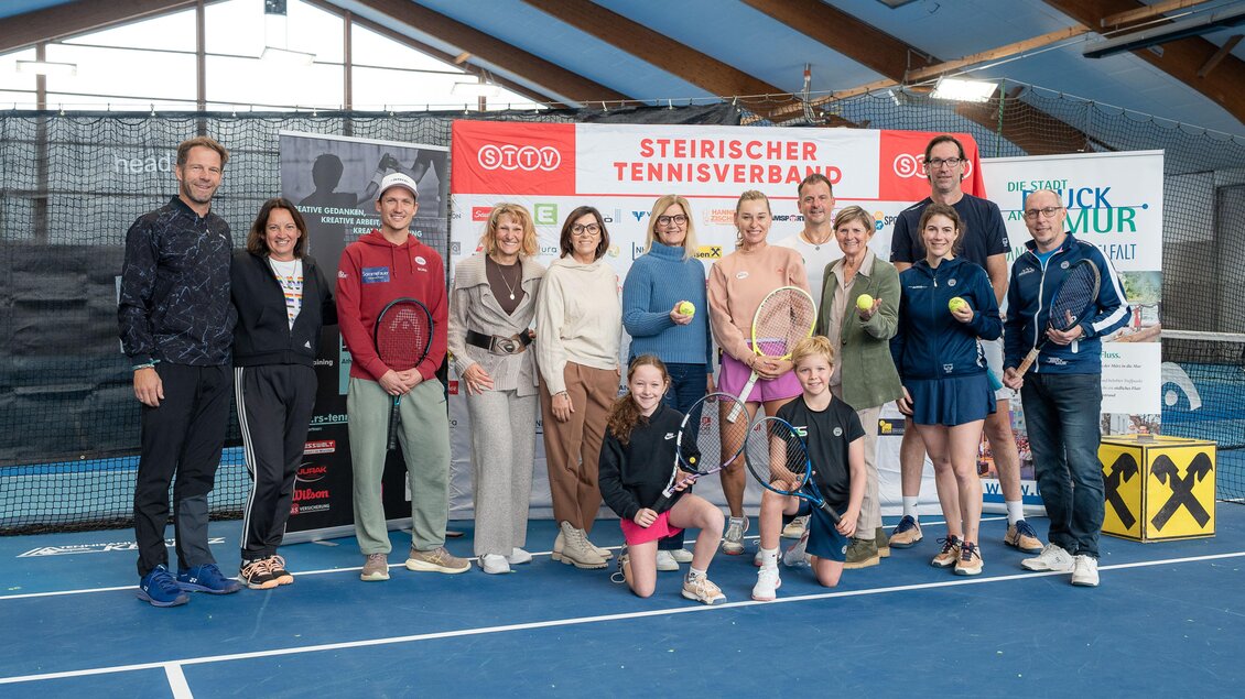 Eine Gruppe von Personen steht zusammengenommen auf einem Tennisplatz. Im Hintergrund ist ein Banner des Steirischen Tennisverbands zu sehen. | © STTV, ESV