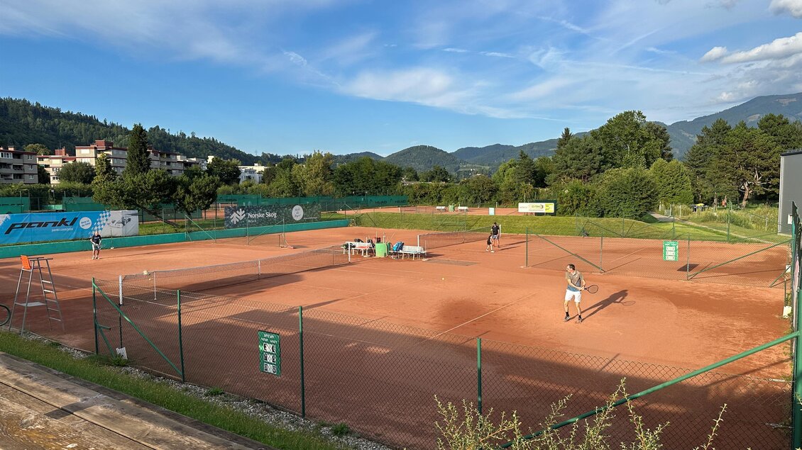 Ein Tennisplatz mit rotem Sand in einer malerischen Umgebung. Spieler trainieren unter einem strahlend blauen Himmel. | © Anna-Lena König