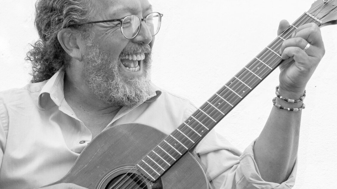 Ein älterer Mann spielt glücklich Gitarre. Er hat eine Brille und einen Bart, und sein Gesicht strahlt Freude aus. | © Oststeiermark Tourismus