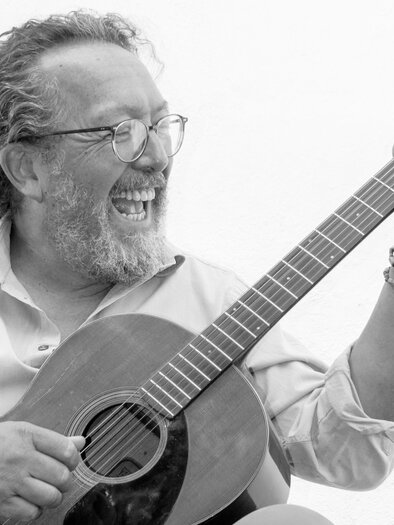 Ein älterer Mann spielt glücklich Gitarre. Er hat eine Brille und einen Bart, und sein Gesicht strahlt Freude aus. | © Oststeiermark Tourismus
