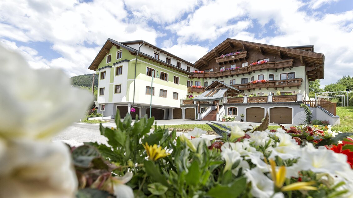Ein charmantes Gebäude mit einem traditionellen alpine Stil, umgeben von bunten Blumen. Der Himmel ist klar und die Umgebung ist grün und einladend. | © GH Donner
