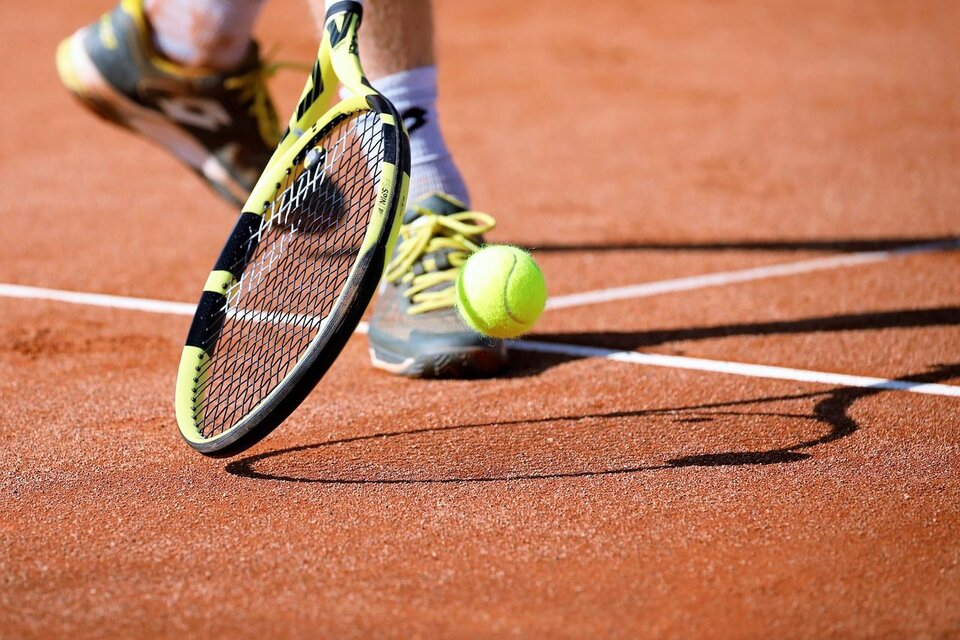 Ein Tennisball springt auf dem Platz, während ein Spieler ihn mit einem Schläger trifft. Die Erde des Platzes ist deutlich sichtbar. | © Pixabay