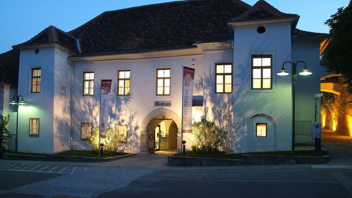 Ein historisches Gebäude bei Nacht, erleuchtet von warmem Licht. Die Fenster sind hell und laden zum Eintreten ein. | © Hans Wetzelsdorfer