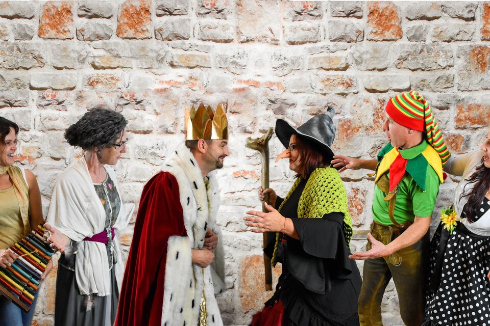 Eine fröhliche Theatergruppe in fantasievollen Kostümen – darunter König, Hexe und weitere Märchenfiguren – steht vor einer rustikalen Ziegelwand. Die lebendige Szene vermittelt Humor, Spielfreude und beste Unterhaltung für die ganze Familie im Zentrum Feldbach. | © SET