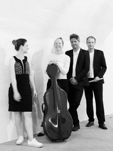 Three women are sitting on a bench and smiling. Next to them lies a cello on the ground. | © Karin Wiedner
