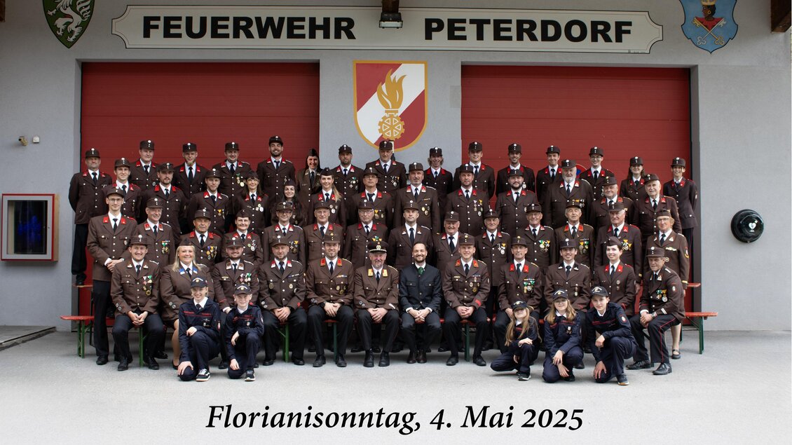 Eine große Gruppe von Feuerwehrleuten steht vor der Feuerwache in Peterdorf. Sie sind in Uniform und feiern den Florianisonntag am 4. Mai 2025.